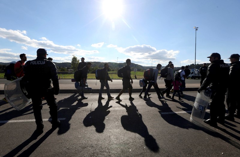 © Reuters. Police officers escort migrants to waiting buses in Obrezje