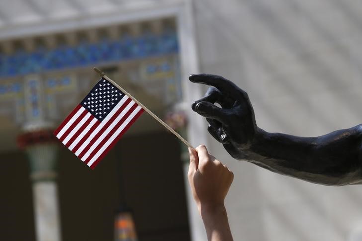 © Reuters. A girl holds a U.S. flag next to a sculpture after a naturalization ceremony at The Metropolitan Museum of Art in New York