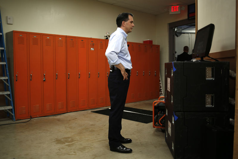 © Reuters. Wisconsin Governor Scott Walker watches his wife Tonette address the crowd as he stands backstage looking at a TV monitor before going out to formally announce his campaign for the 2016 Republican presidential nomination in Waukesha