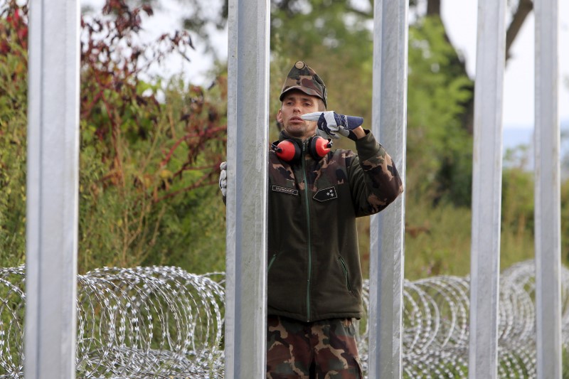 © Reuters. A Hungarian army soldier gestures as others build a fence on the border with Croatia near Sarok