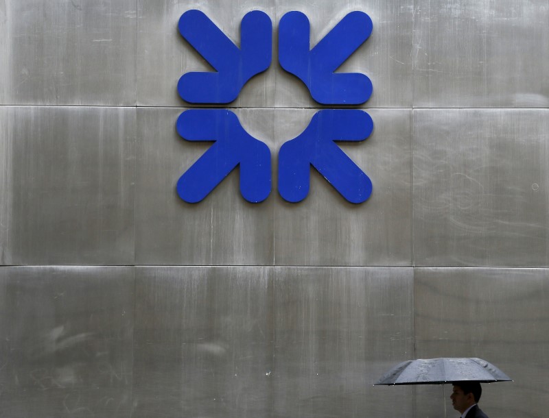 © Reuters. File photo of a man taking shelter under an umbrella as he walks past a branch of RBS in the City of London