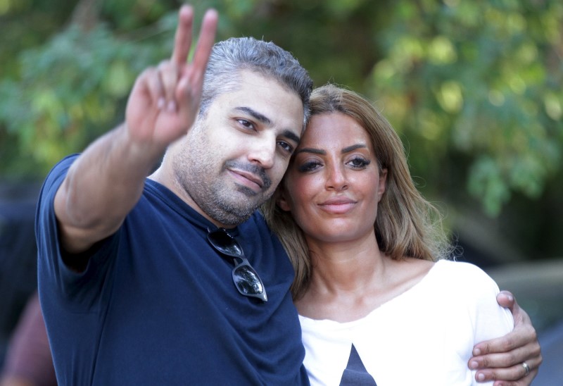 © Reuters. Al Jazeera television journalist Mohamed Fahmy flashes the victory sign as he celebrates with his wife Marwa Omara after being released from Tora prison, in Cairo