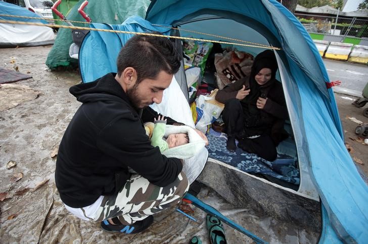 © Reuters. Refugiado sírio Ehab Ali Naser segura bebê em acampamento em Paris