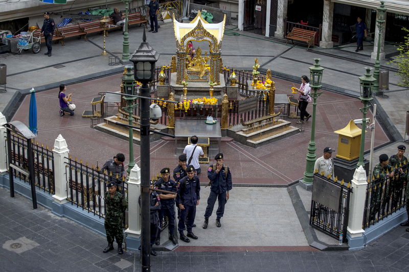 © Reuters. Thai police stand guard as people pray during a crime re-enactment near the bomb site at Erawan shrine in central Bangkok