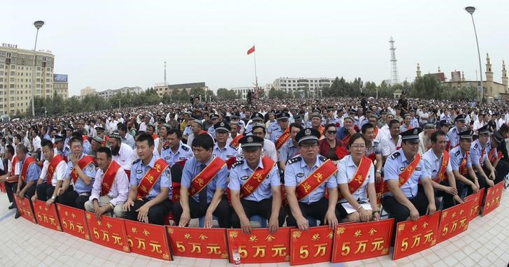 © Reuters. Police wearing sashes hold placards during a ceremony to award those who the authorities say participated in "the crackdown of violence and terrorists activities" in Hotan