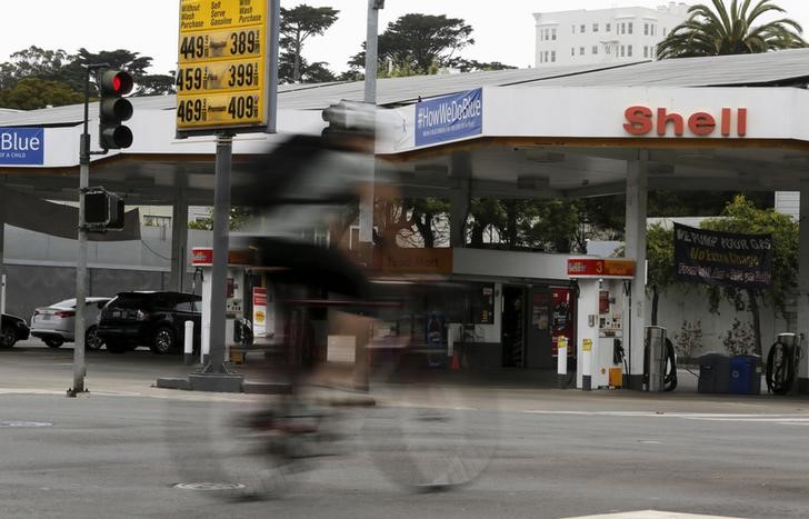 © Reuters. A cyclist rides past sign showing prices of gas at filling station in San Francisco