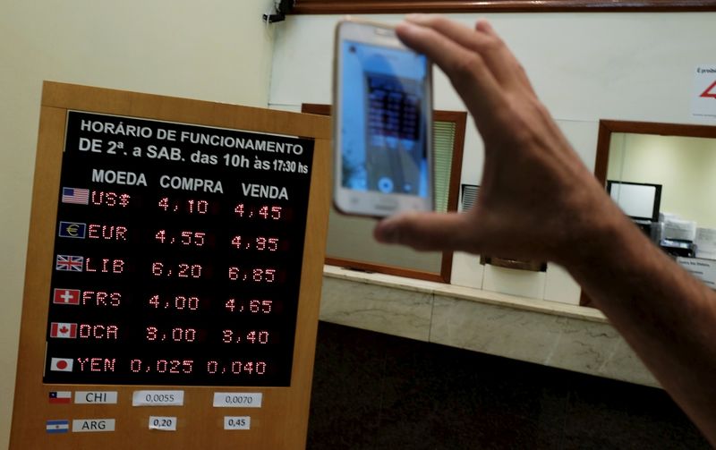 © Reuters. Homem tira foto de quadro com cotações de moedas em loja de câmbio em São Paulo