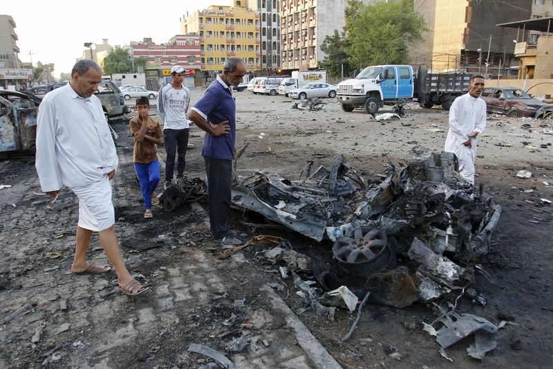 © Reuters. Residents look at wreckage at the site of a car bomb attack in Baghdad, Iraq