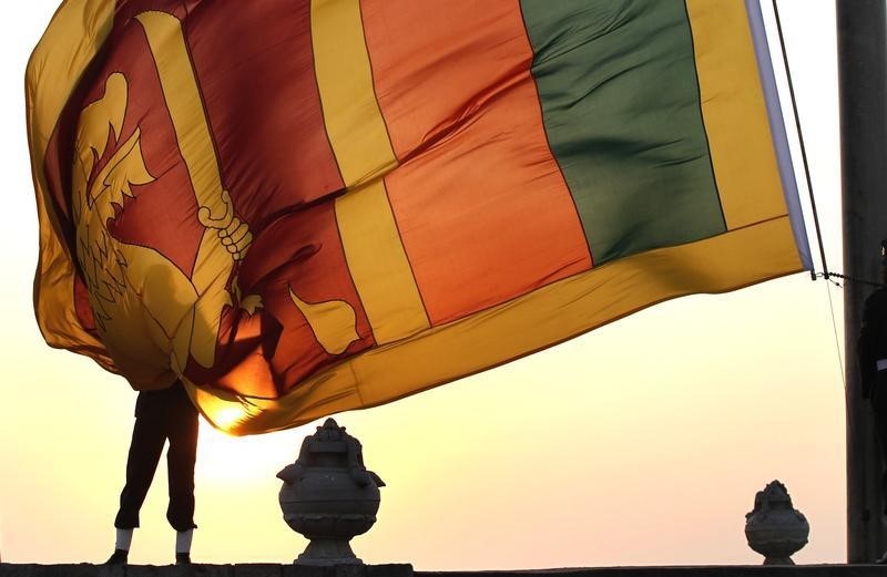 © Reuters. An air force officer holds the Sri Lanka national flag as the sun sets at galle face green in  Colombo