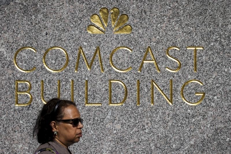 © Reuters. A woman walks past the NBC logo and Comcast at 30 Rockefeller Plaza in Manhattan, New York