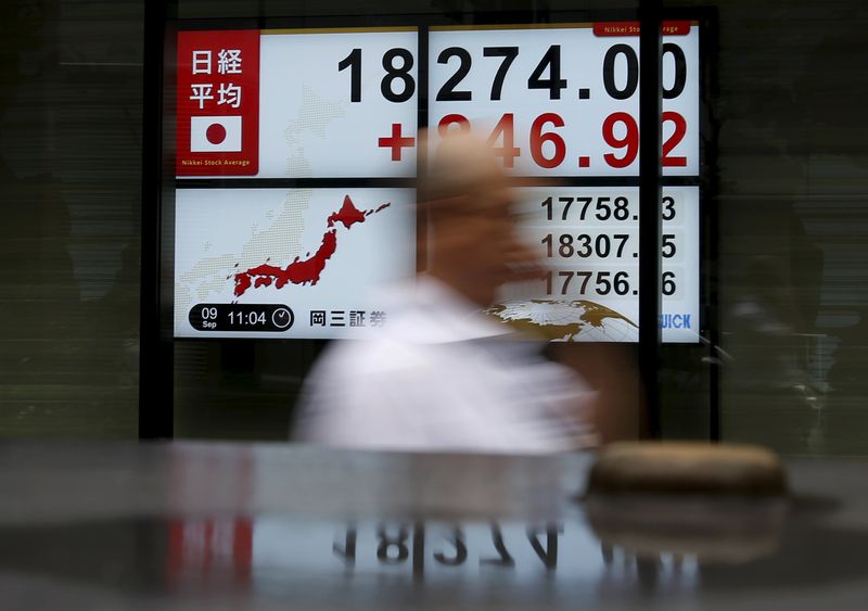 © Reuters. A pedestrian walks past electronic boards showing the Japan's Nikkei average outside a brokerage in Tokyo