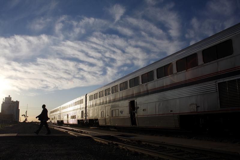 © Reuters. An Amtrak train attendant walks across the tracks at the Holdrege station