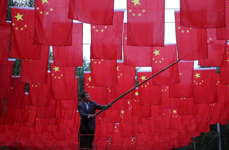 © Reuters. Homem decorando parque com bandeiras chinesas em Pequim
