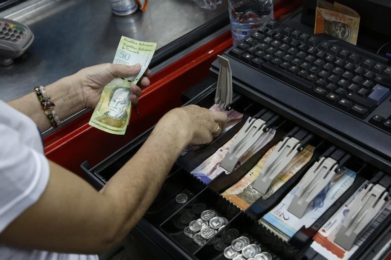 © Reuters. A cashier counts Venezuelan bolivar notes at a supermarket checkout line in Caracas