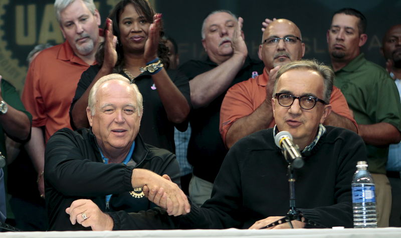 © Reuters. Fiat Chrysler Automobiles (FCA) CEO Sergio Marchionne and United Auto Workers union President Dennis Williams shake hands during a news conference in Detroit