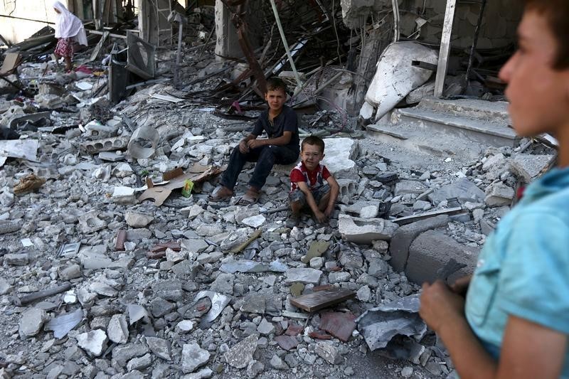 © Reuters. Children sit atop of debris after what activists said was an airstrike by forces loyal to Asaad at Arbin town in Damascus countryside, Syria