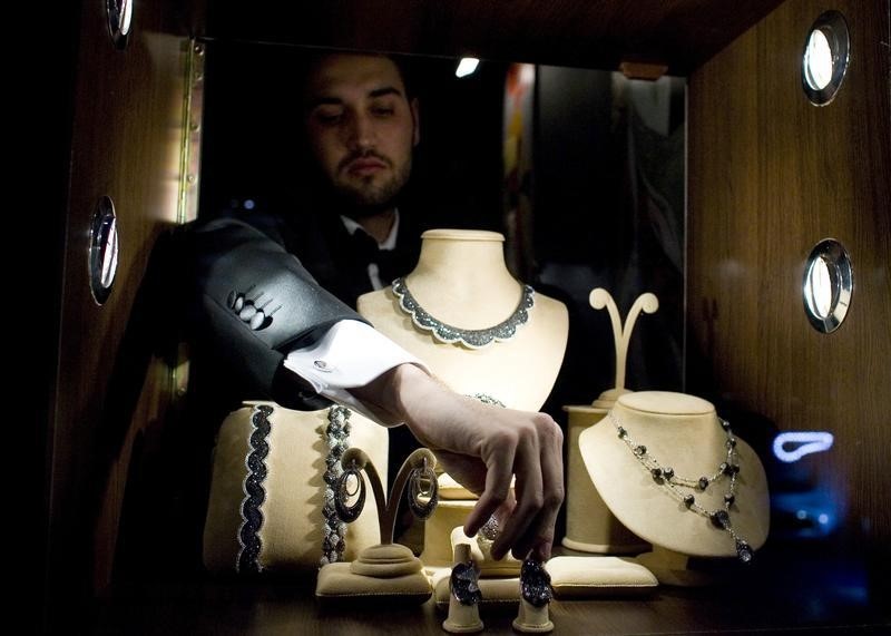© Reuters. Работник выставки Millionaire Fair раскладывает на стенде ювелирные украшения