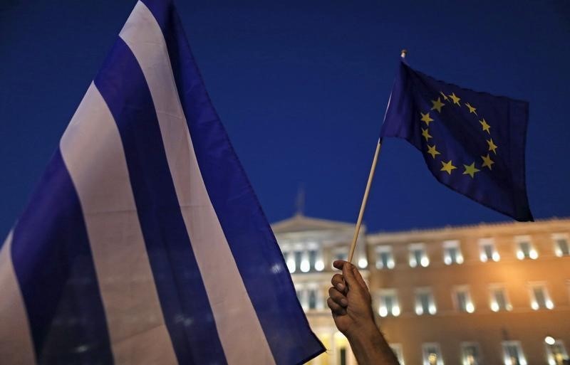 © Reuters. Protesters hold European Union and Greek flags during a Pro-Euro rally in front of the parliament building in Athens
