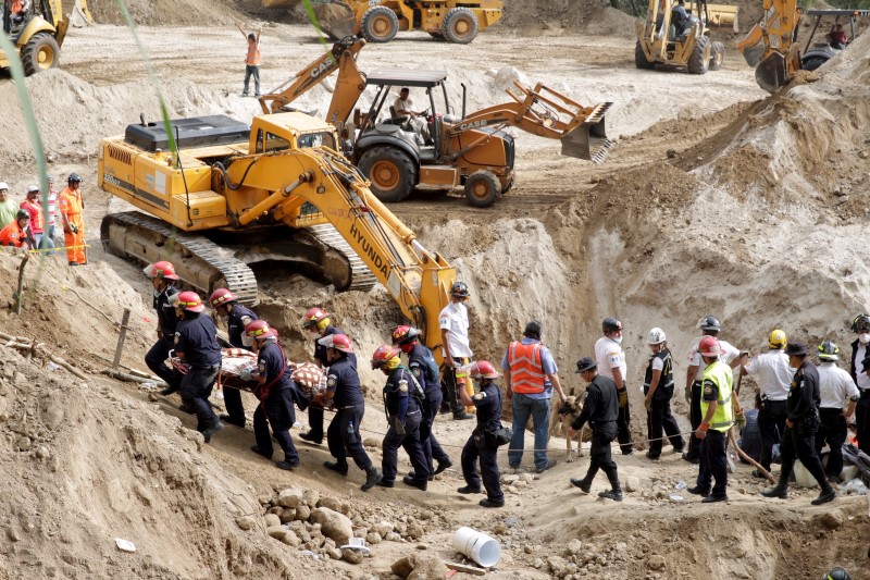 © Reuters. Rescue team members carry the body of a mudslide victim in Santa Catarina Pinula, on the outskirts of Guatemala City