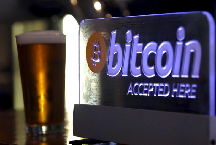 © Reuters. A beer poured for a customer sits on a bar next to a Bitcoin sign in central Sydney, Australia