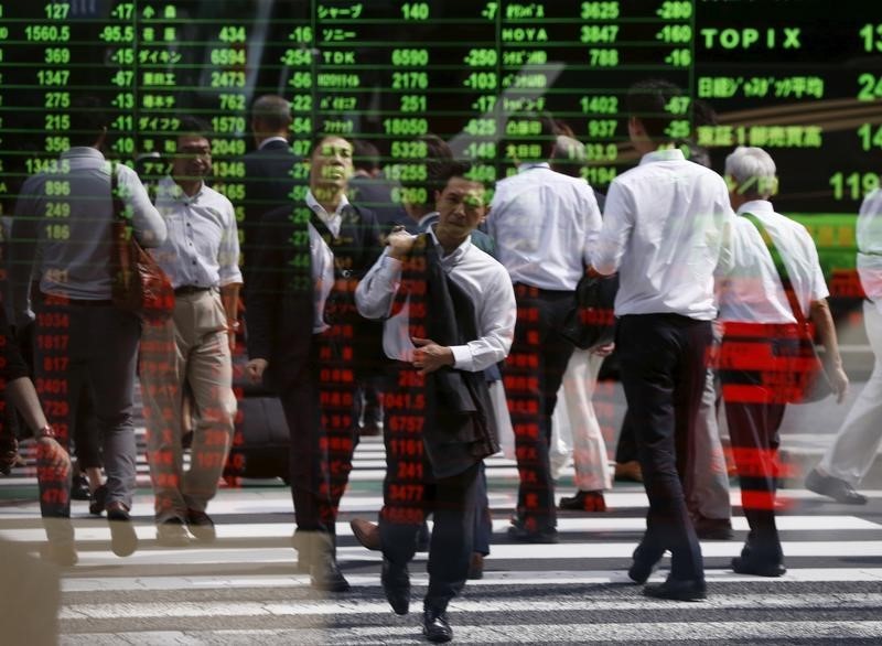 © Reuters. Passersby are reflected on a stock quotation board at a brokerage in Tokyo