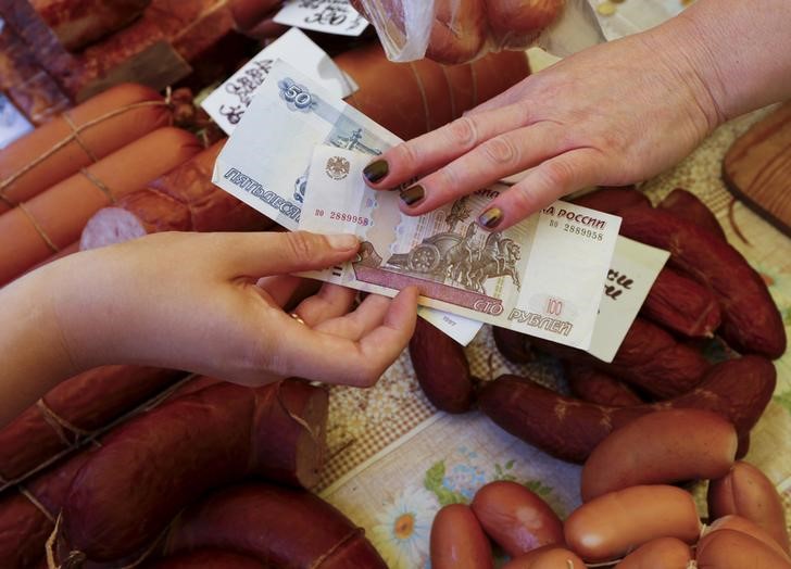 © Reuters. Покупатель платит продавцу за продукты на рынке в Красноярске