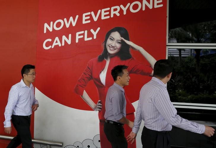 © Reuters. Men walk past an AirAsia sales centre in Kuala Lumpur, Malaysia
