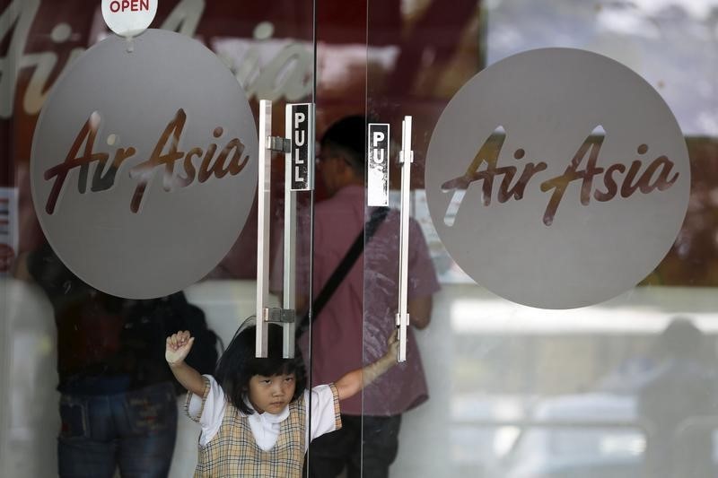 © Reuters. A girl pushes the door of an AirAisia ticketing office at Soekarno-Hatta Airport in Jakarta
