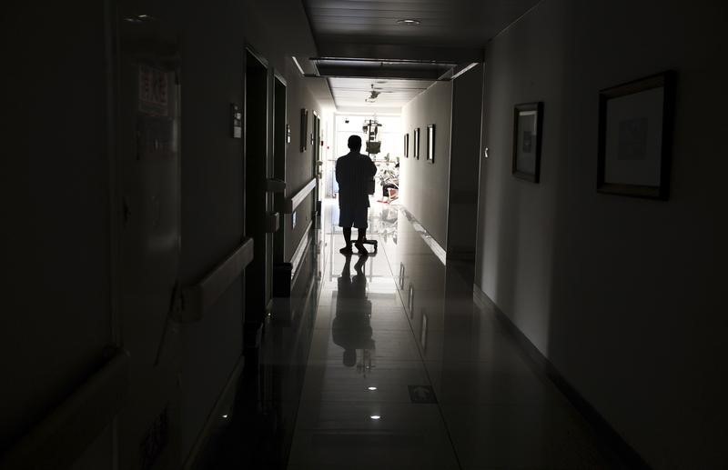 © Reuters. A cancer patient pushes his drip stand as he walks down the hallway of the Beijing Cancer Hospital