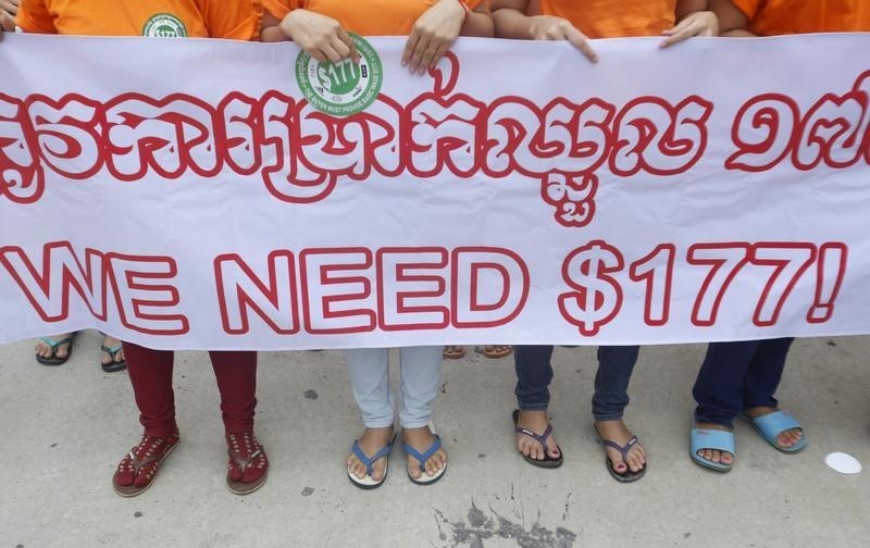 © Reuters. Garment workers hold a banner during a protest calling for higher wages in Phnom Penh