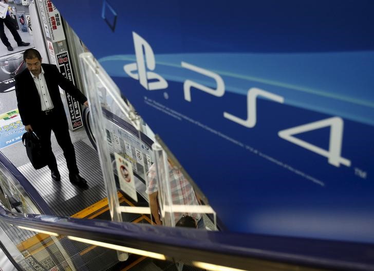 © Reuters. A man rides an escalator under a advertisement board of Sony Corp's PlayStation 4 game console at an electronics retailer in Tokyo