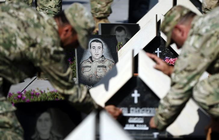 © Reuters. Soldiers light candles in memory of the Georgian soldiers killed during Georgia's war conflict with Russia over the breakaway region of South Ossetia in 2008, at the memorial cemetery in Tbilisi