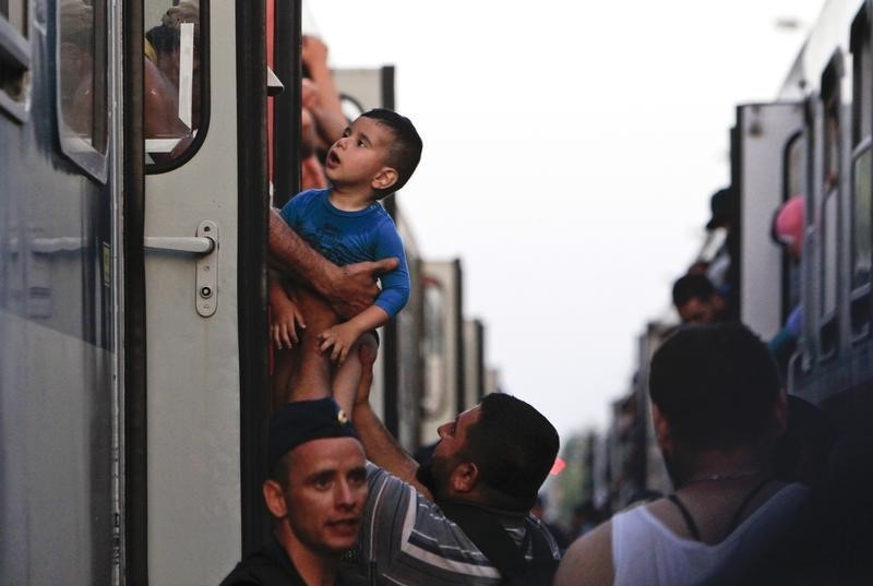 © Reuters. A migrants holds a child while they leave a train after arriving at a train station in Magyarboly