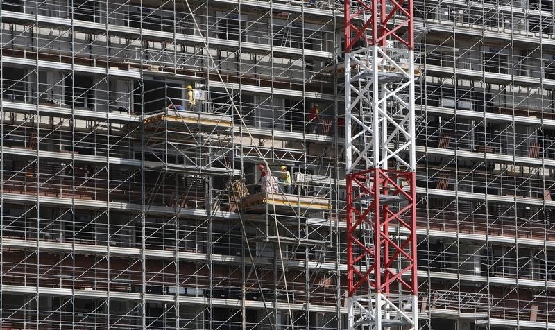 © Reuters. Labourers work at the scaffolding of a building in downtown Milan