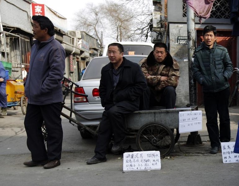 © Reuters. Jobseekers with signs mentioning their skills wait for employers at a market street in a Hutong, Chinese for 