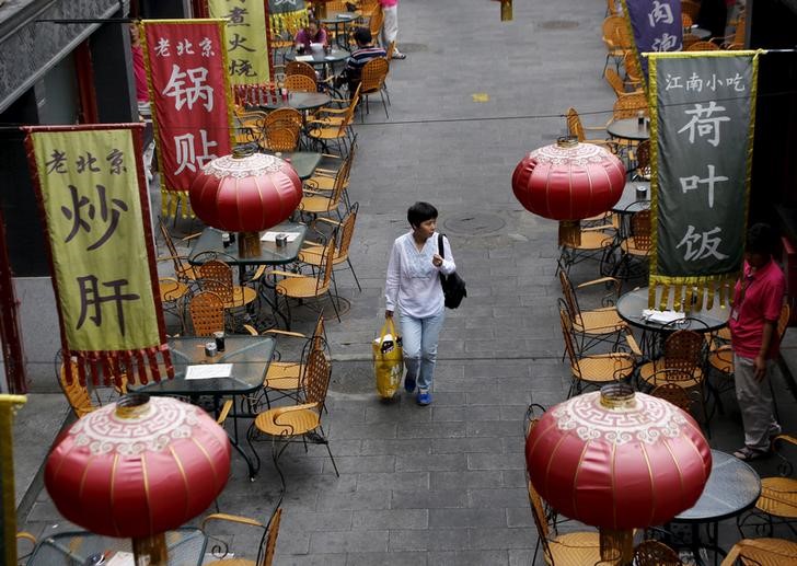 © Reuters. A woman carrying a shopping bag walks underneath lanterns of a restaurant in a shopping district of Beijing