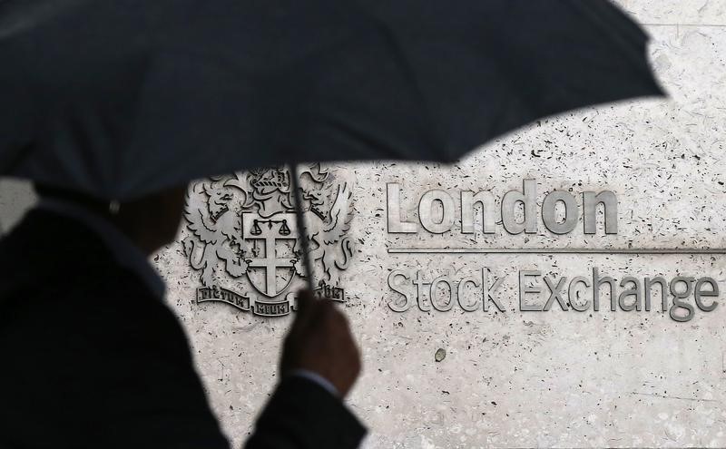 © Reuters. A man shelters under an umbrella as he walks past the London Stock Exchange 
