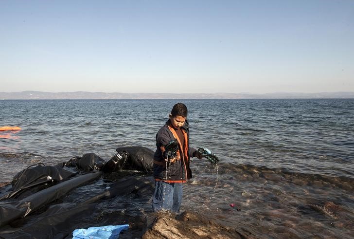 © Reuters. Criança imigrante tirando água de seu sapato na ilha grega de Lesbos