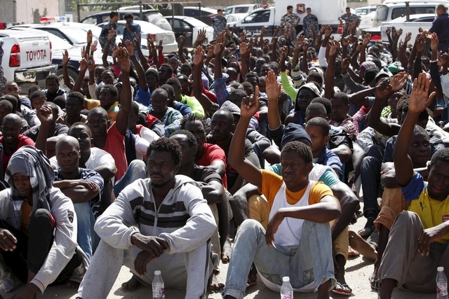 © Reuters. Illegal migrants sit at a temporary detention centre after they were detained by Libyan authorities in Tripoli