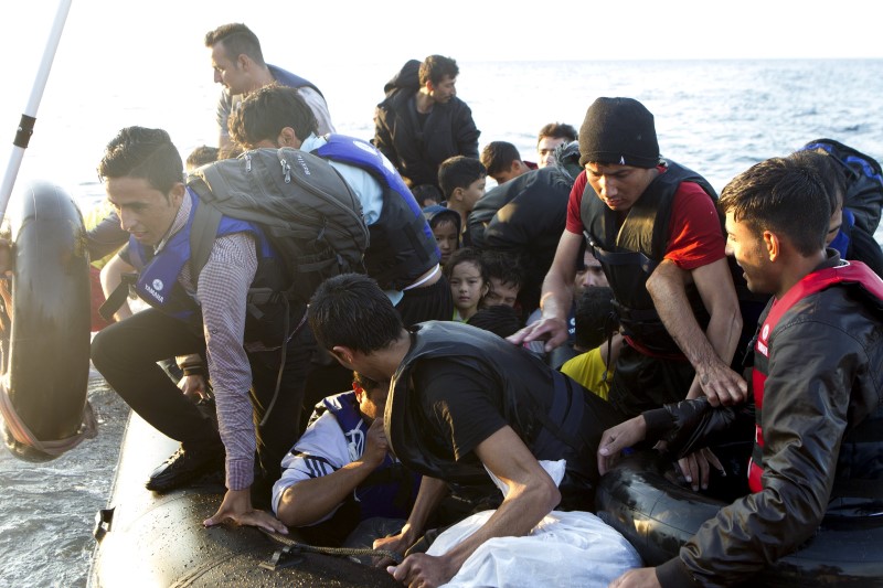 © Reuters. Refugiados afegãos saltam de bote em chegada à ilha grega de Lesbos após travessia a partir da Turquia