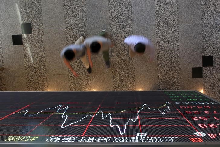 © Reuters. People walk under an electronic board showing stock information at the Shanghai Stock Exchange in Lujiazui Financial Area in Shanghai