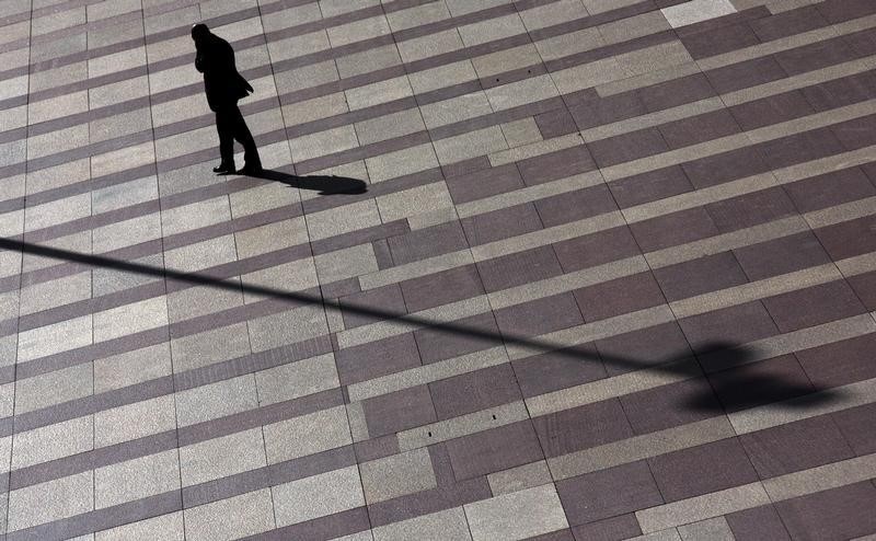 © Reuters. Man talks on mobile phone as he walks on a patterned floor at a yard outside an office building in Madrid's financial district