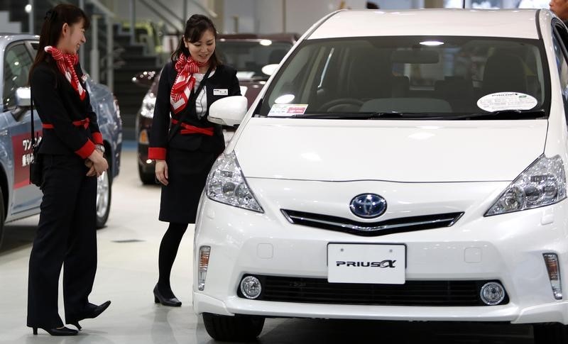© Reuters. Showroom staff chat next to a Toyota Motor Corp Prius Alpha at its showroom in Tokyo