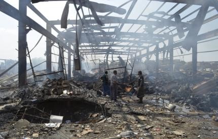 © Reuters. Men walk at the site of a Saudi-led air strike targeted at Public Electricity Corporation branch in Yemen's western city of Hodeidah