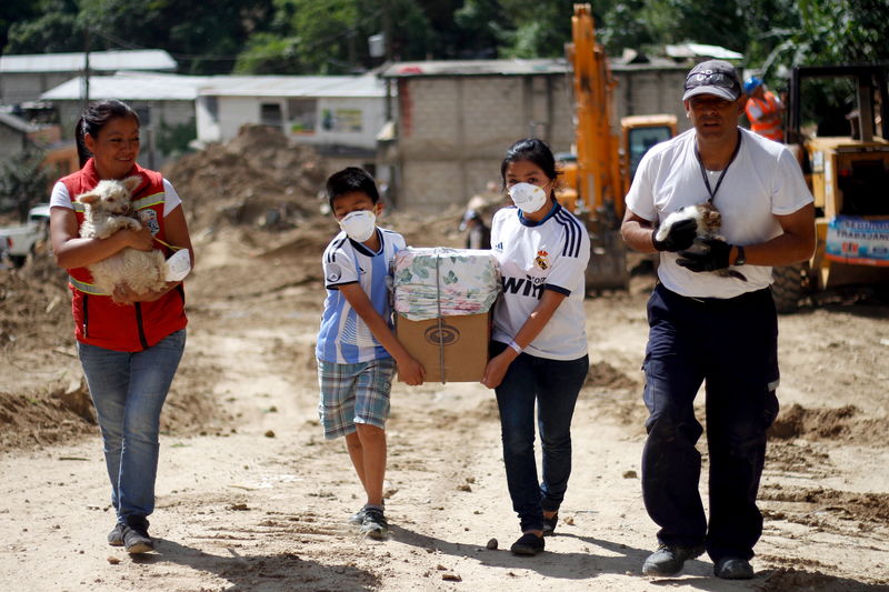 © Reuters. Moradores carregam pertences após deslizamento em Santa Catarina Pinula, Guatemala 