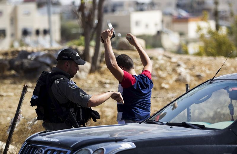 © Reuters. Policial israelense revistando palestino em Jerusalém