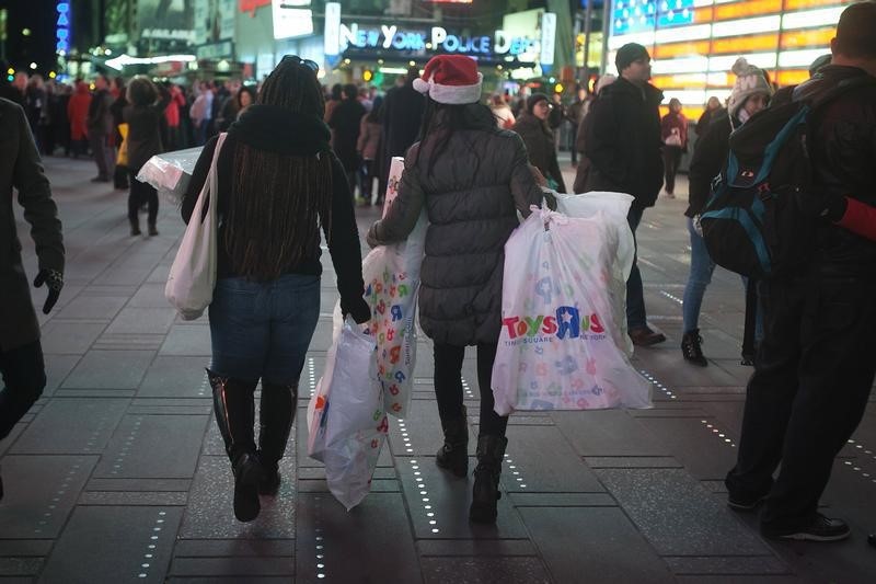 © Reuters. Women make their way though Times Square with bags of purchases from Toys R Us in New York