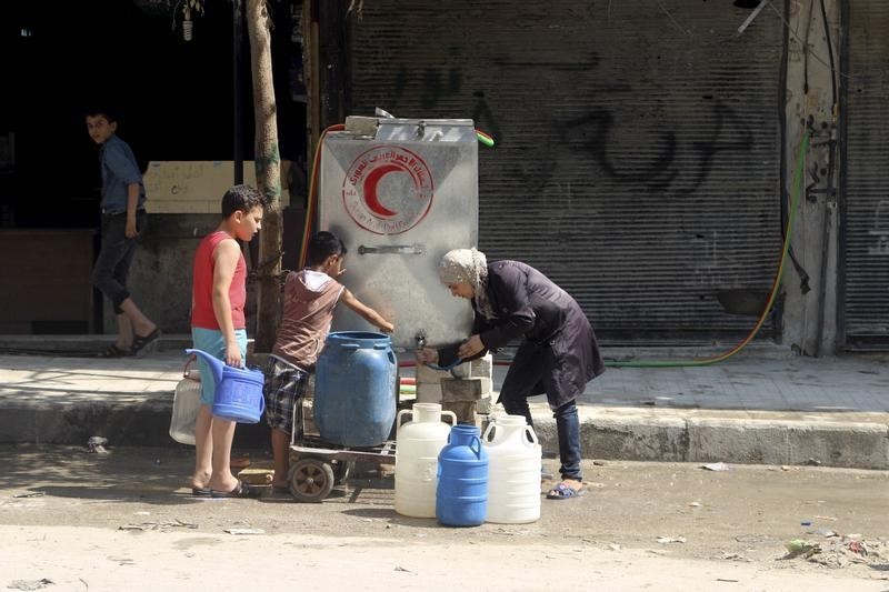 © Reuters. Moradores enchem recipientes com água em Aleppo