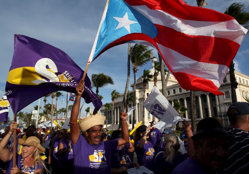 © Reuters. A member of a labor union shouts slogans while holding a Puerto Rico flag during a protest in San Juan