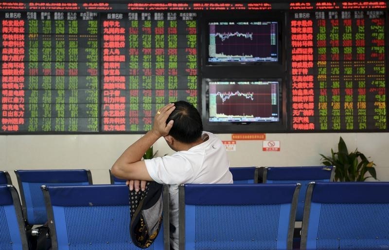 © Reuters. An investor sits in front of an electronic board showing stock information at brokerage house in Fuyang